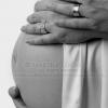 Black and white close up of bare pregnant belly with husband and wife's hands