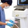 Product shot of Bioptics lab equipment with technician with blue gloves and face mask