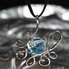 Modern pendant necklace hanging in front of silvery reflective background